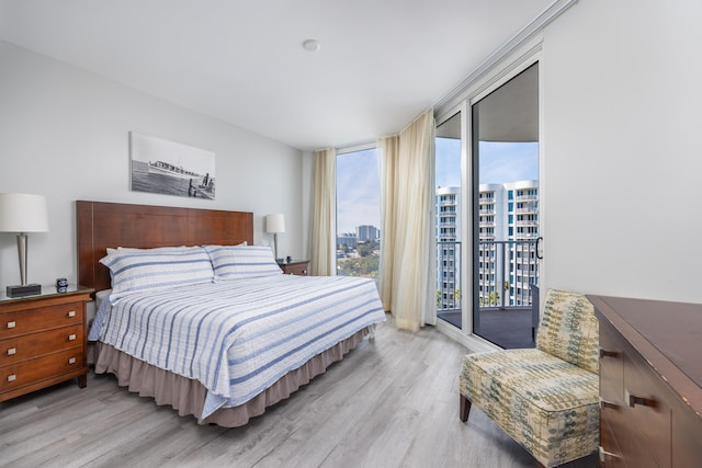 bedroom featuring floor to ceiling windows, access to exterior, light hardwood / wood-style floors, and multiple windows