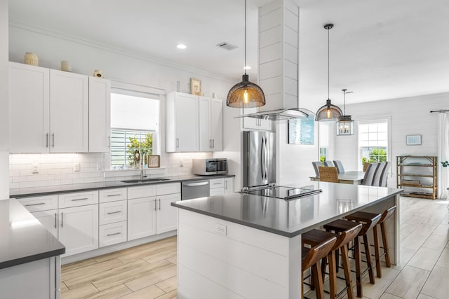 kitchen with decorative light fixtures, appliances with stainless steel finishes, tasteful backsplash, and a healthy amount of sunlight