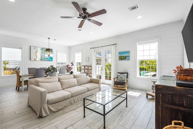 living room with french doors, ceiling fan, and light wood-type flooring