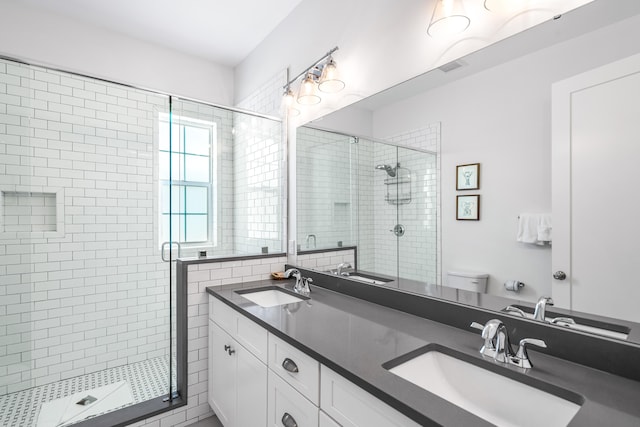 bathroom with double sink vanity, toilet, and walk in shower