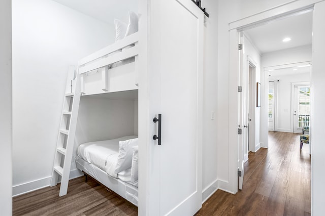 bedroom with a barn door and dark hardwood / wood-style flooring