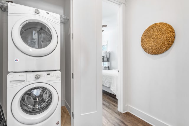 laundry area with hardwood / wood-style floors and stacked washer and dryer