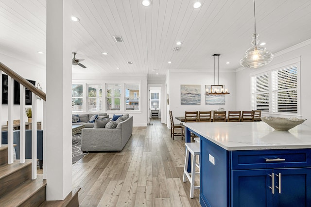 kitchen featuring hanging light fixtures, ceiling fan with notable chandelier, crown molding, light hardwood / wood-style flooring, and blue cabinetry