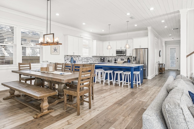 dining area with ornamental molding, light hardwood / wood-style flooring, and a chandelier