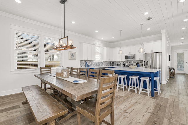 dining area featuring a healthy amount of sunlight, light wood-type flooring, and crown molding