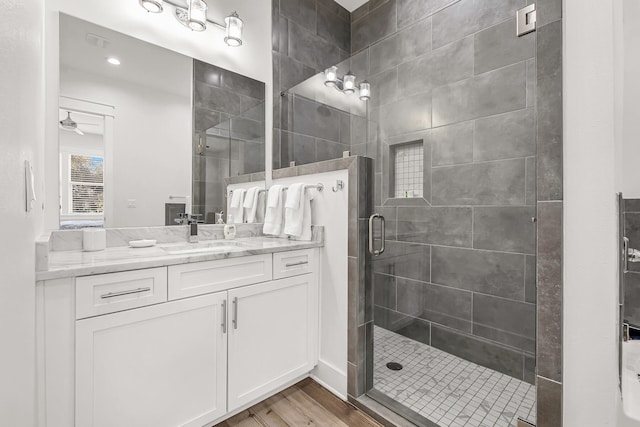 bathroom with ceiling fan, vanity, hardwood / wood-style flooring, and a shower with door