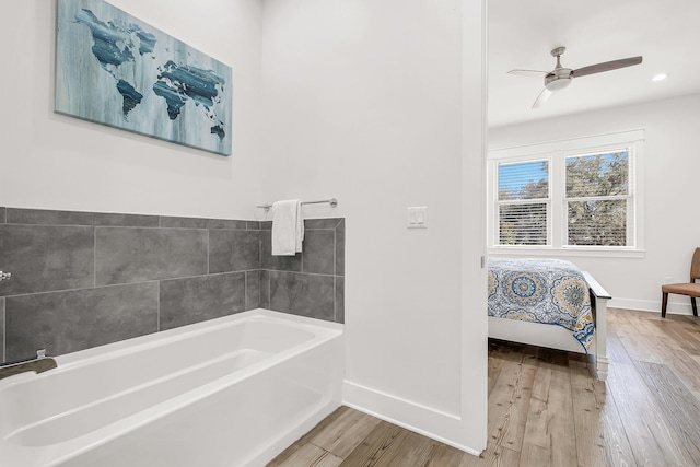 bathroom featuring ceiling fan, a washtub, and hardwood / wood-style flooring