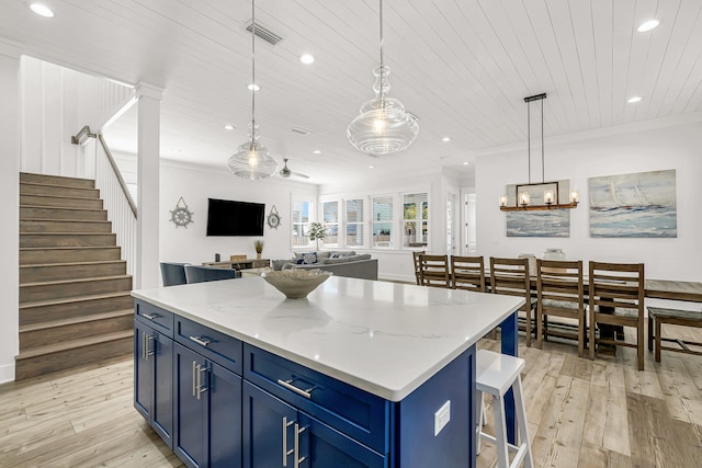 kitchen featuring hanging light fixtures, light hardwood / wood-style flooring, a center island, and ornamental molding