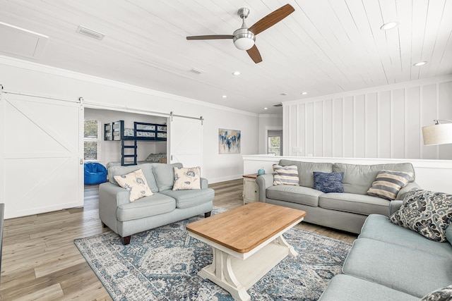 living room with light hardwood / wood-style flooring, ornamental molding, a barn door, wood ceiling, and ceiling fan