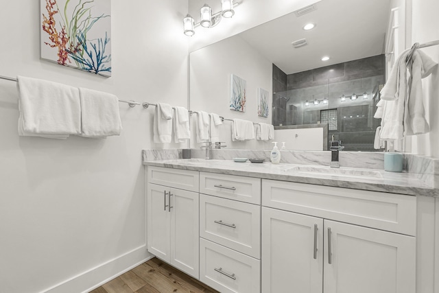 bathroom with hardwood / wood-style flooring, a shower with shower door, and dual vanity