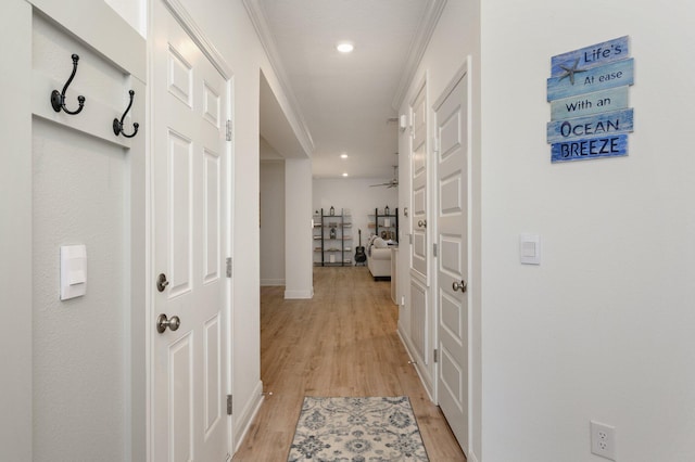 corridor with light wood-type flooring and ornamental molding