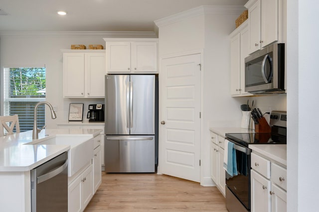 kitchen with white cabinetry, sink, stainless steel appliances, crown molding, and light wood-type flooring