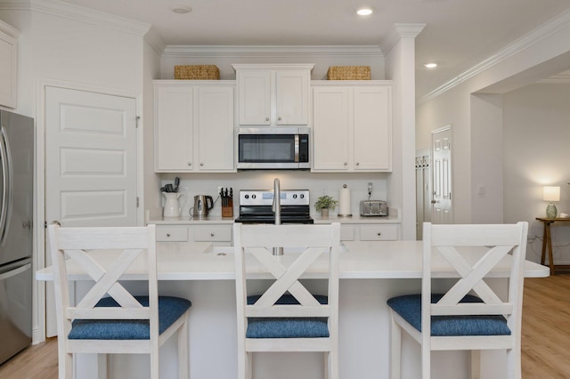 kitchen featuring stainless steel appliances, white cabinetry, and a breakfast bar area