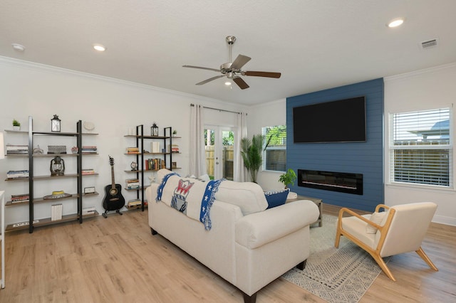 living room featuring a large fireplace, light hardwood / wood-style floors, and ornamental molding