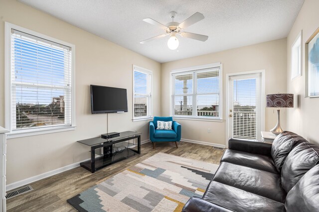 living room featuring a textured ceiling, ceiling fan, and dark wood-type flooring