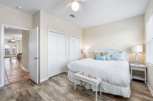 bedroom featuring ceiling fan, two closets, and light tile flooring