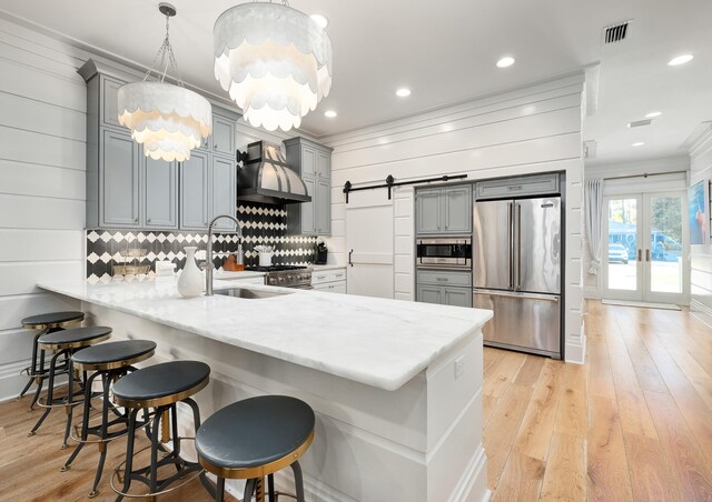 kitchen with hanging light fixtures, backsplash, a breakfast bar area, premium appliances, and wall chimney exhaust hood