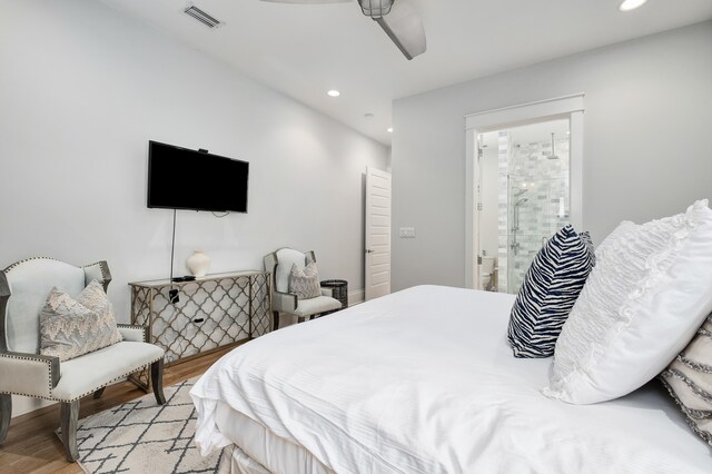 bedroom featuring light hardwood / wood-style floors, ceiling fan, and ensuite bath