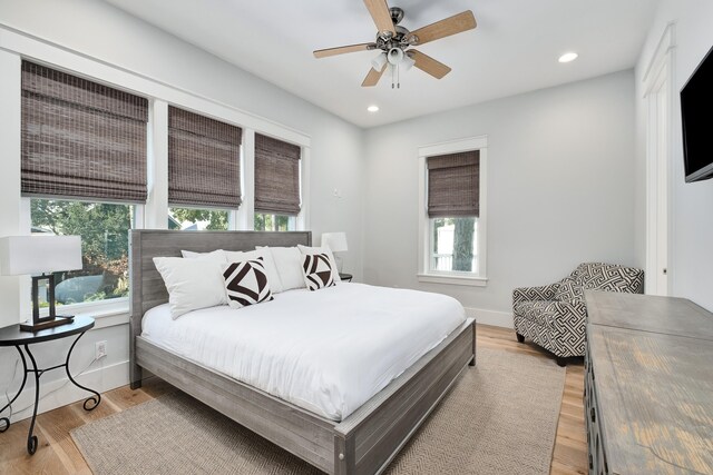 bedroom with light hardwood / wood-style flooring, ceiling fan, and multiple windows