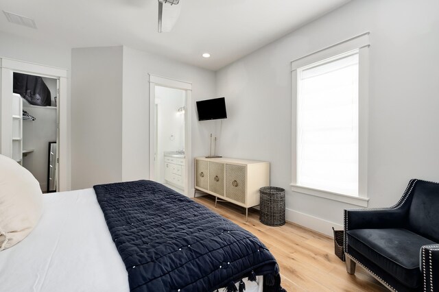 bedroom featuring ensuite bath, hardwood / wood-style floors, and multiple windows