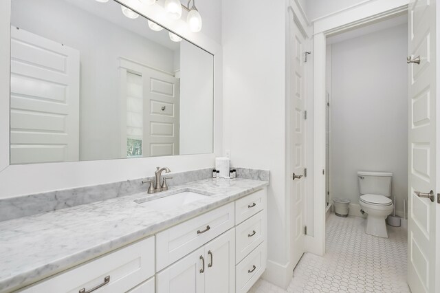 bathroom featuring tile floors, vanity, and toilet