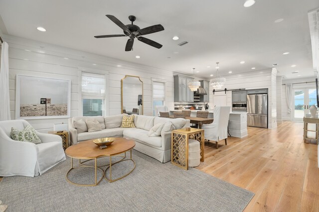 living room with light hardwood / wood-style flooring, ceiling fan, and a barn door