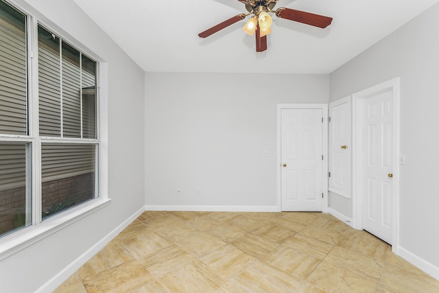 spare room with ceiling fan and light tile flooring