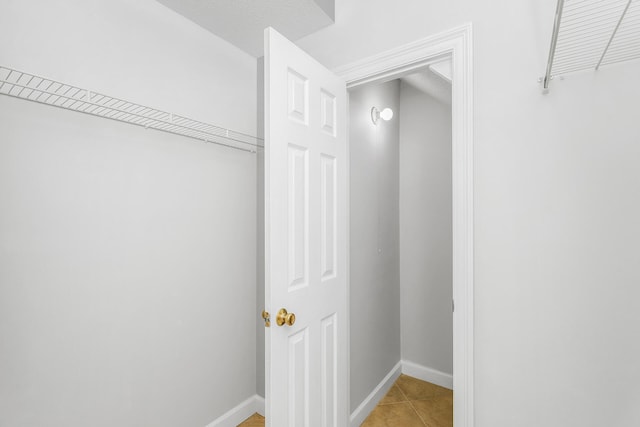 walk in closet with light tile floors