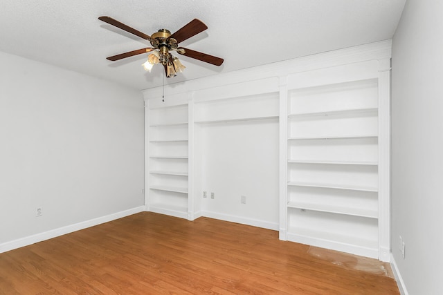 spare room featuring built in features, ceiling fan, a textured ceiling, and light wood-type flooring