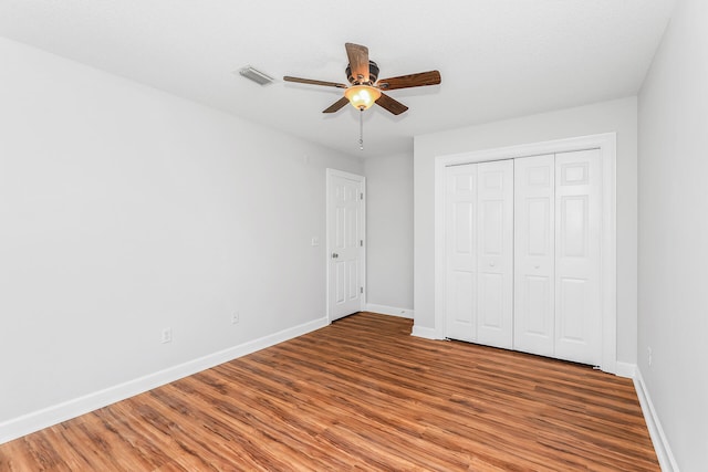 unfurnished bedroom with hardwood / wood-style floors, a closet, and ceiling fan