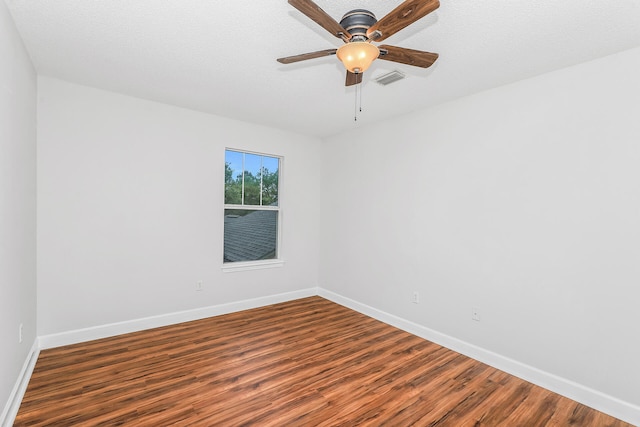 empty room featuring dark hardwood / wood-style floors, ceiling fan, and a textured ceiling