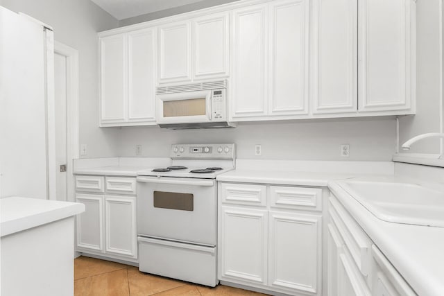 kitchen with white cabinets, sink, white appliances, and light tile flooring