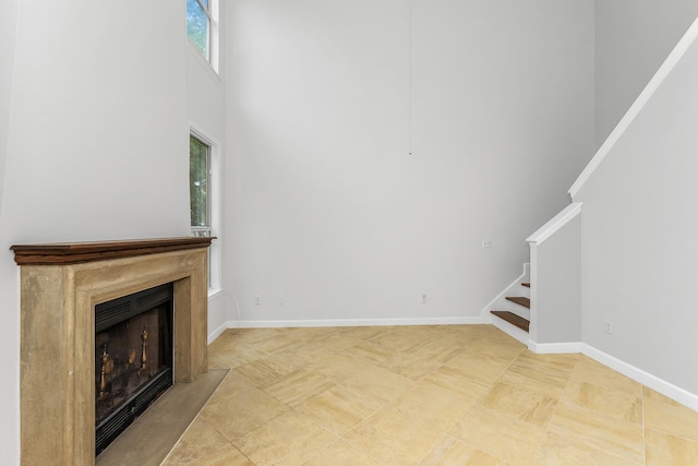 unfurnished living room featuring a high ceiling and light tile floors