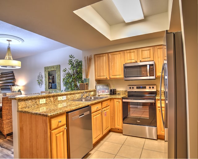 kitchen with light stone countertops, kitchen peninsula, stainless steel appliances, light tile floors, and sink