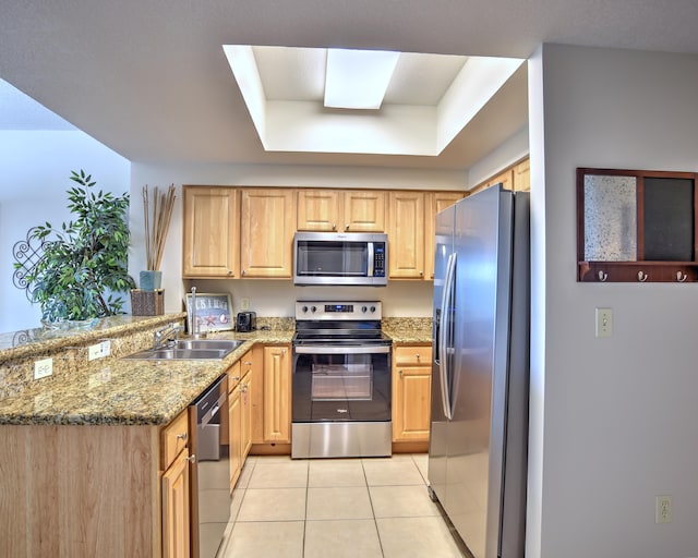 kitchen with light stone countertops, stainless steel appliances, a skylight, sink, and light tile floors