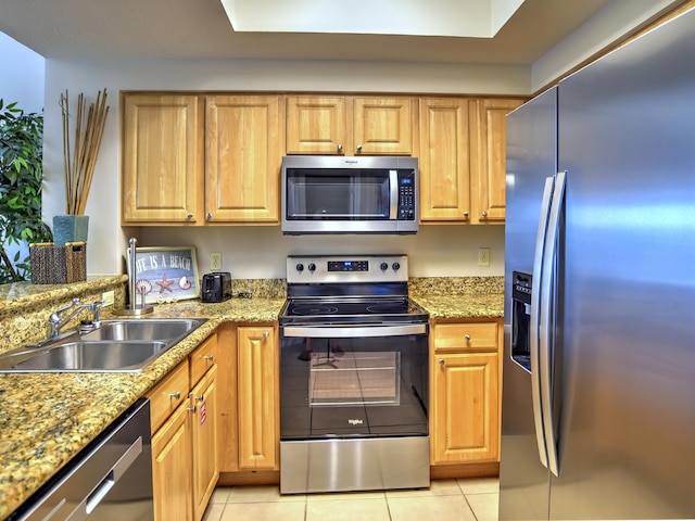 kitchen with sink, stainless steel appliances, light tile flooring, and light stone counters