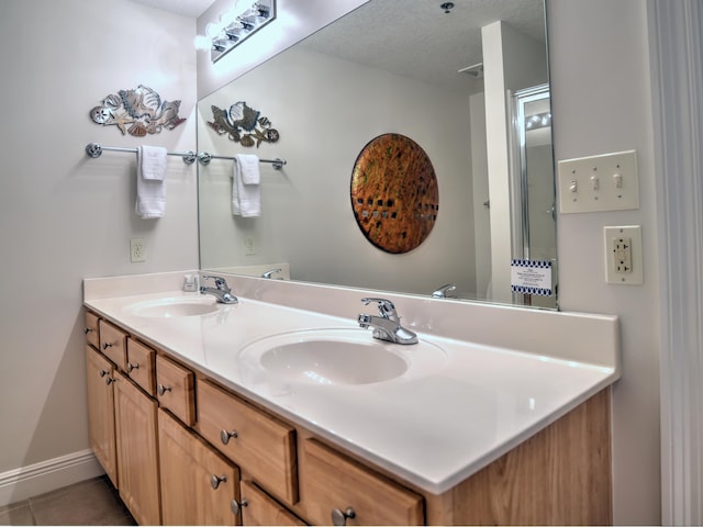 bathroom featuring dual sinks, oversized vanity, a textured ceiling, and tile flooring