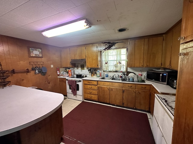 kitchen featuring wood walls, white electric stove, stove, sink, and light tile floors