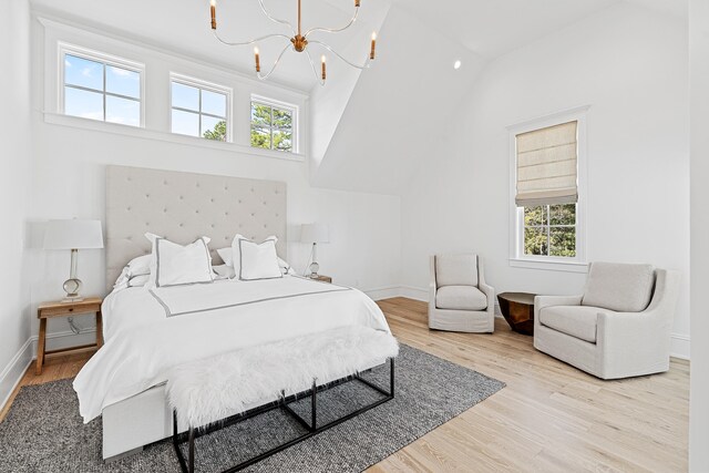 bedroom featuring lofted ceiling, light hardwood / wood-style floors, and a chandelier