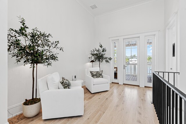 sitting room featuring light hardwood / wood-style flooring, a high ceiling, and ornamental molding