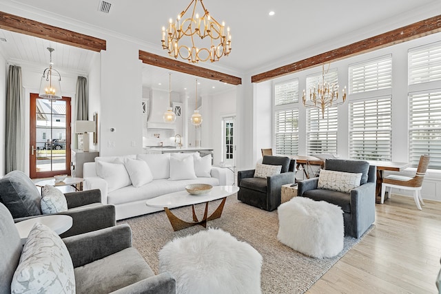 living room featuring a wealth of natural light, ornamental molding, light hardwood / wood-style flooring, and a notable chandelier