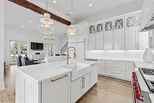 kitchen featuring tasteful backsplash, pendant lighting, a kitchen island with sink, and white cabinetry