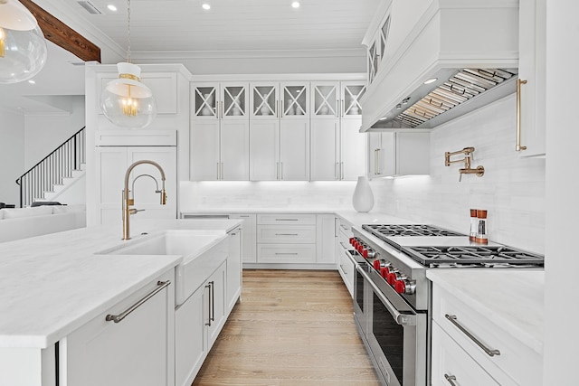 kitchen with range with two ovens, backsplash, custom exhaust hood, and pendant lighting