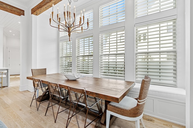 dining area with an inviting chandelier, light hardwood / wood-style flooring, beamed ceiling, and a high ceiling