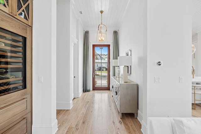 foyer entrance featuring beverage cooler, light hardwood / wood-style floors, and crown molding