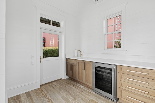 bar with wine cooler and light hardwood / wood-style flooring