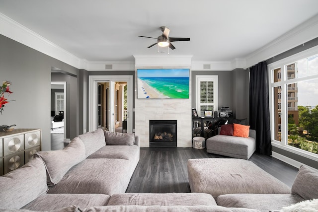 living room featuring a tile fireplace, dark wood-type flooring, ceiling fan, and ornamental molding