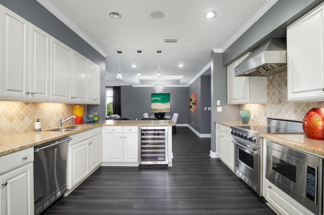 kitchen featuring white cabinets, wall chimney range hood, decorative light fixtures, kitchen peninsula, and stainless steel appliances