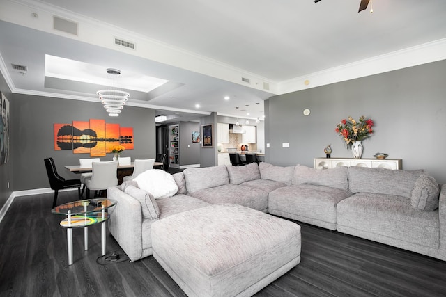 living room with ornamental molding, a tray ceiling, dark hardwood / wood-style floors, and ceiling fan with notable chandelier