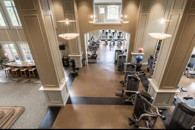 workout area featuring decorative columns and a high ceiling